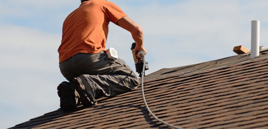 A photo of a roofer using a Pneumatic Coil Roofing Nailer to nail shingles into roof